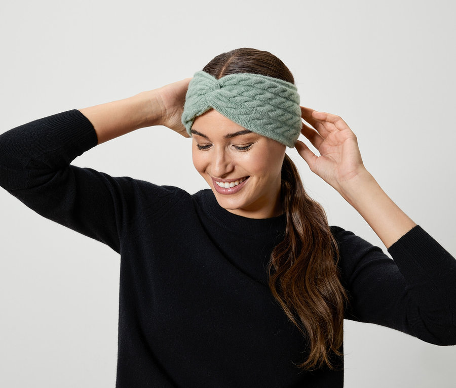 Femme ajustant un bandeau tricoté vert clair.