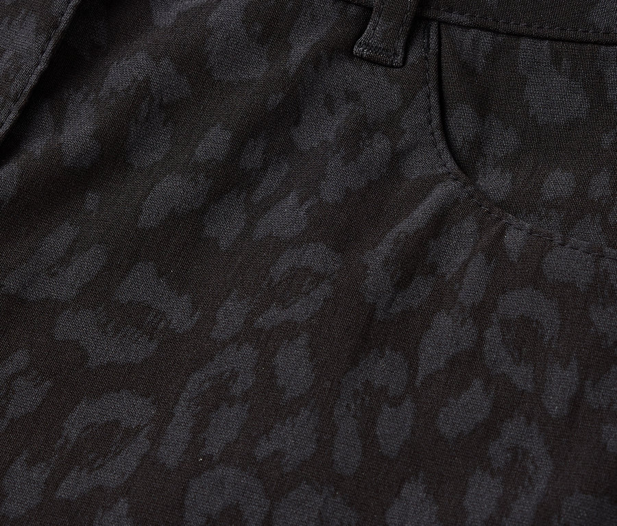 Gros plan sur un pantalon noir à motif léopard, avec un bouton et une poche.