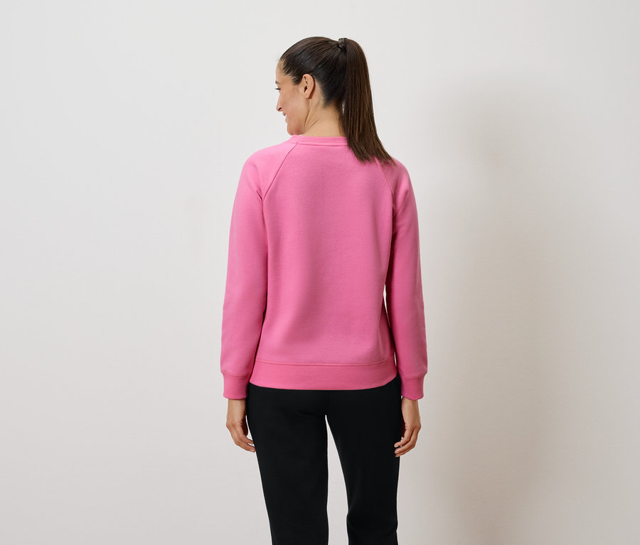 Une femme portant un sweat-shirt rose et un pantalon noir, vue de dos.