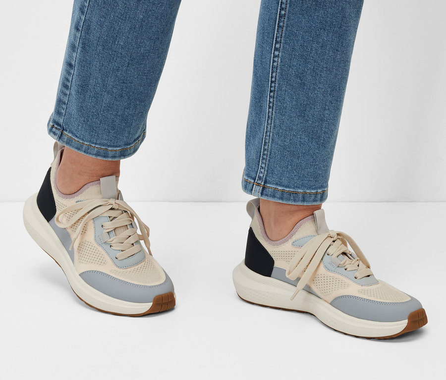 Jambes en jean et baskets sur fond blanc.