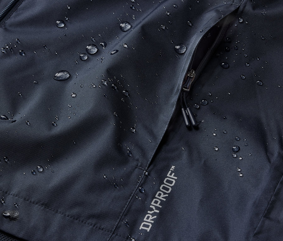 Détail d'une veste de pluie bleu marine avec poche zippée et inscription DRYPROOF.