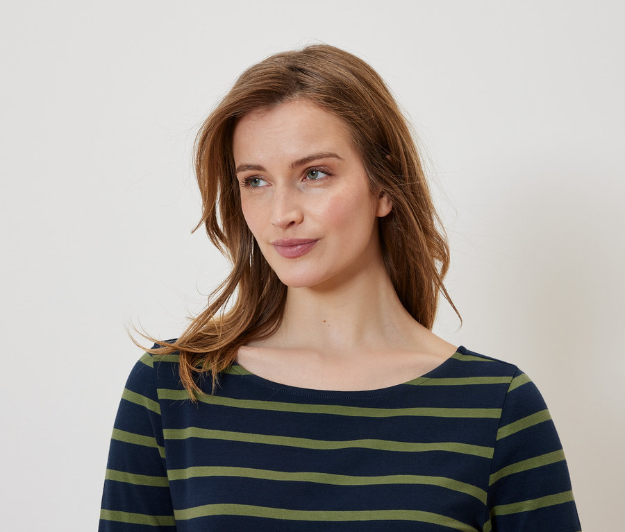 Portrait d'une femme aux cheveux bruns portant un t-shirt rayé bleu et vert.