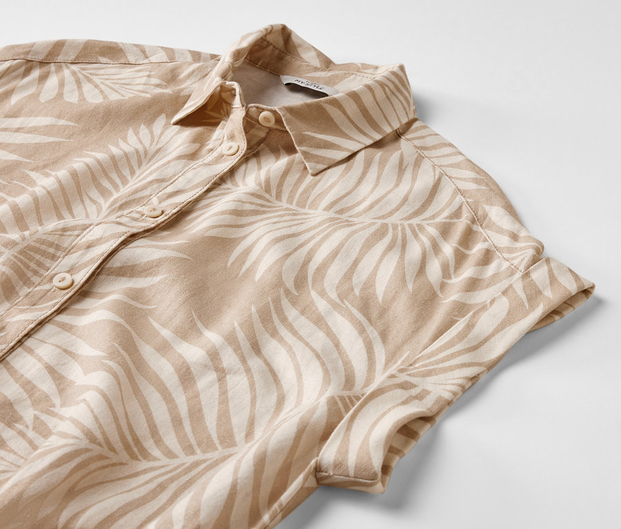 Gros plan sur une robe en lin imprimée avec des manches courtes et des boutons.