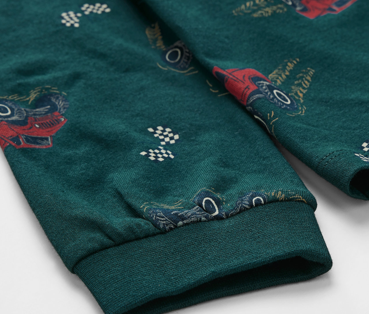 Gros plan sur un pyjama vert pour enfant avec un motif de camions.