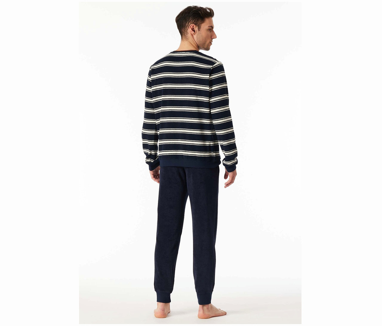 Un homme, vu de dos, porte un haut rayé et un pantalon bleu marine.