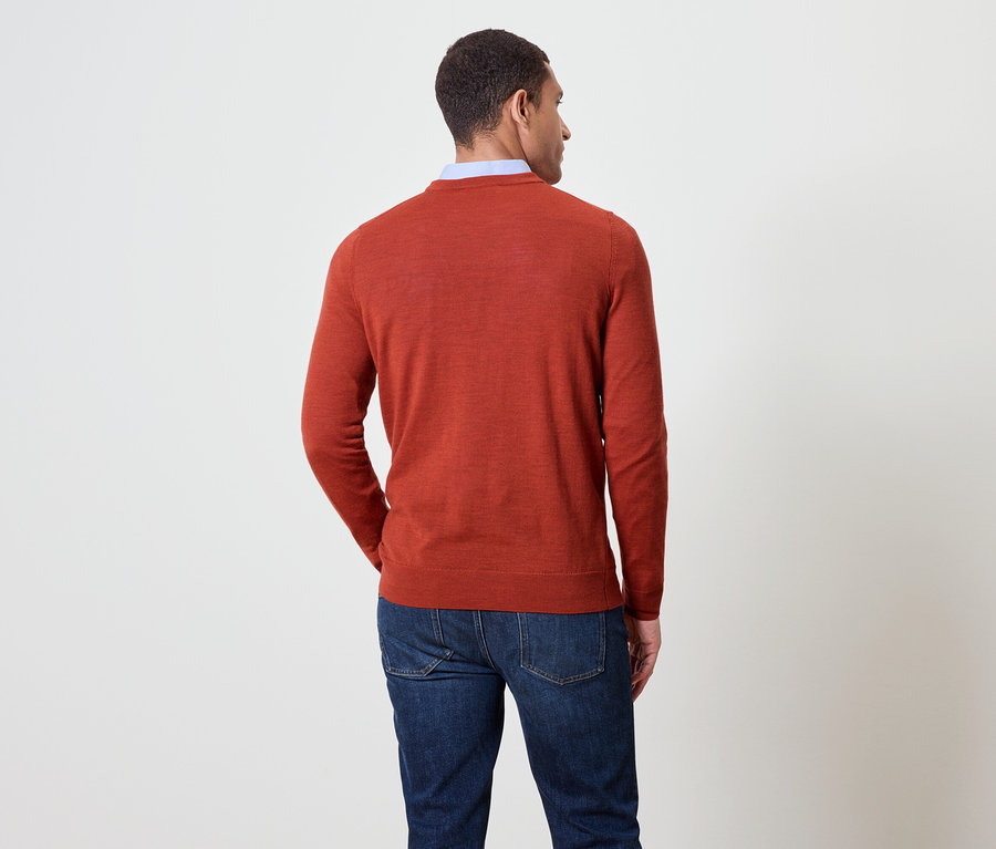 Un homme vu de dos porte un pull orange et un jean bleu.