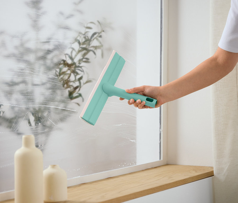 Une personne nettoie une fenêtre avec une raclette.