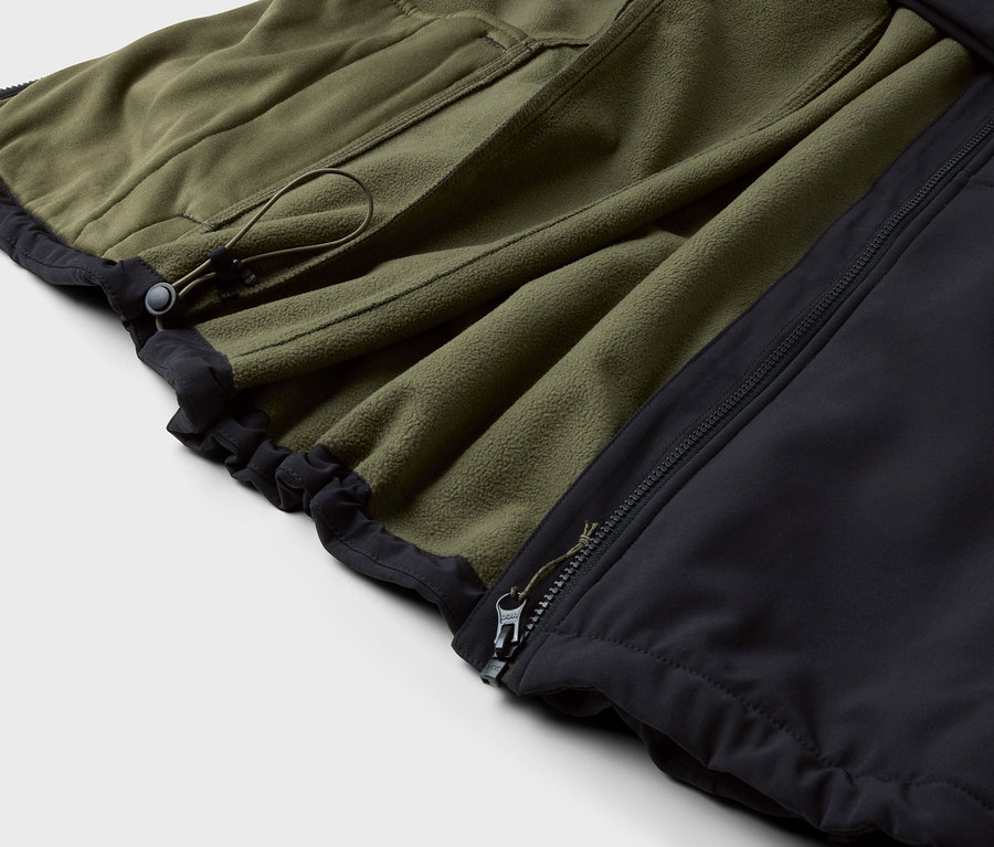 Gros plan d'une veste en polaire vert olive avec bordure noire et fermeture éclair.