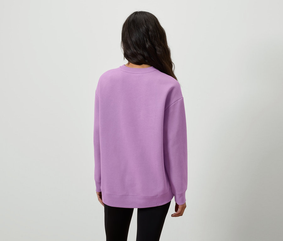 Vue arrière d'une femme aux longs cheveux noirs portant un pull lilas et un legging noir.