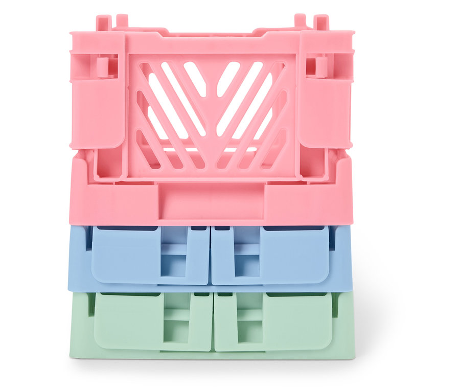 Pile de trois caisses pliantes en plastique : rose, bleue et verte.