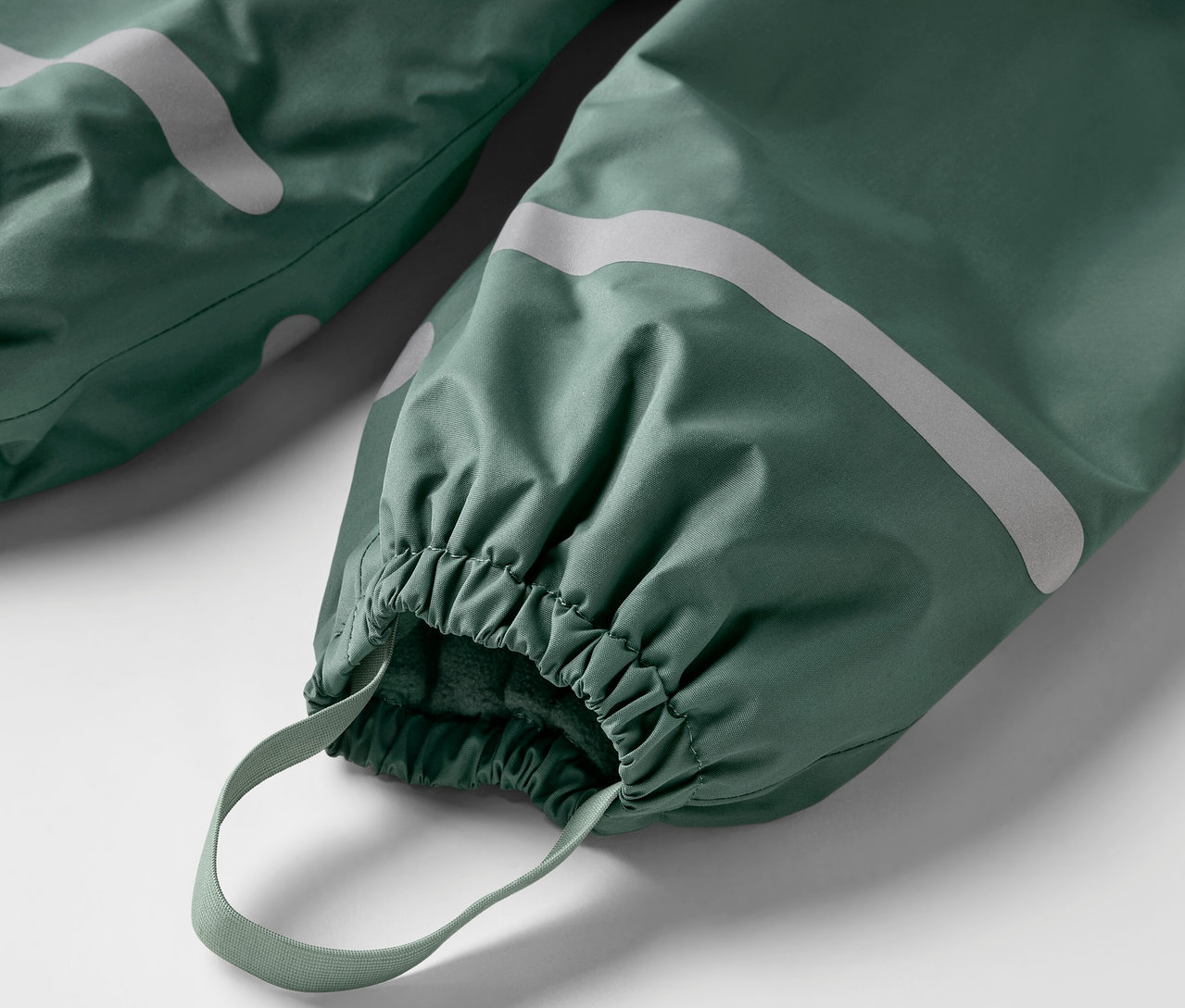 Gros plan sur un pantalon de pluie thermique pour enfant, vert.