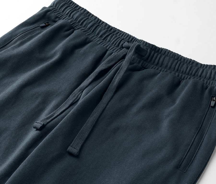 Gros plan d'un pantalon de survêtement bleu foncé avec cordon de serrage et poches zippées.