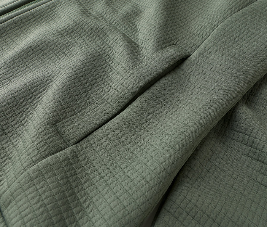 Gros plan d'une veste vert olive avec fermeture éclair et poche.