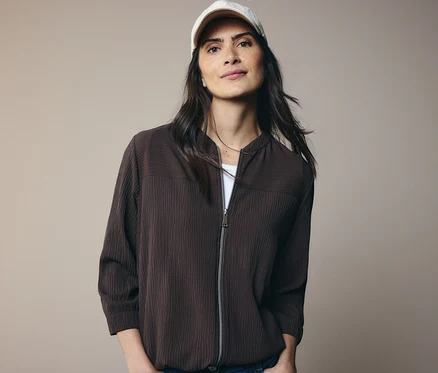 Femme portant une veste marron et une casquette blanche.