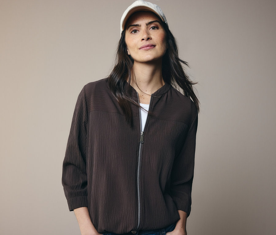 Femme portant une veste marron et une casquette blanche.