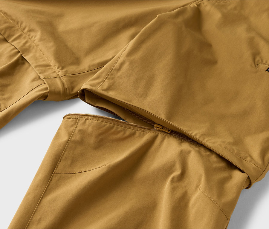 Gros plan d'un pantalon kaki avec une jambe zippée partiellement fixée par une fermeture éclair.