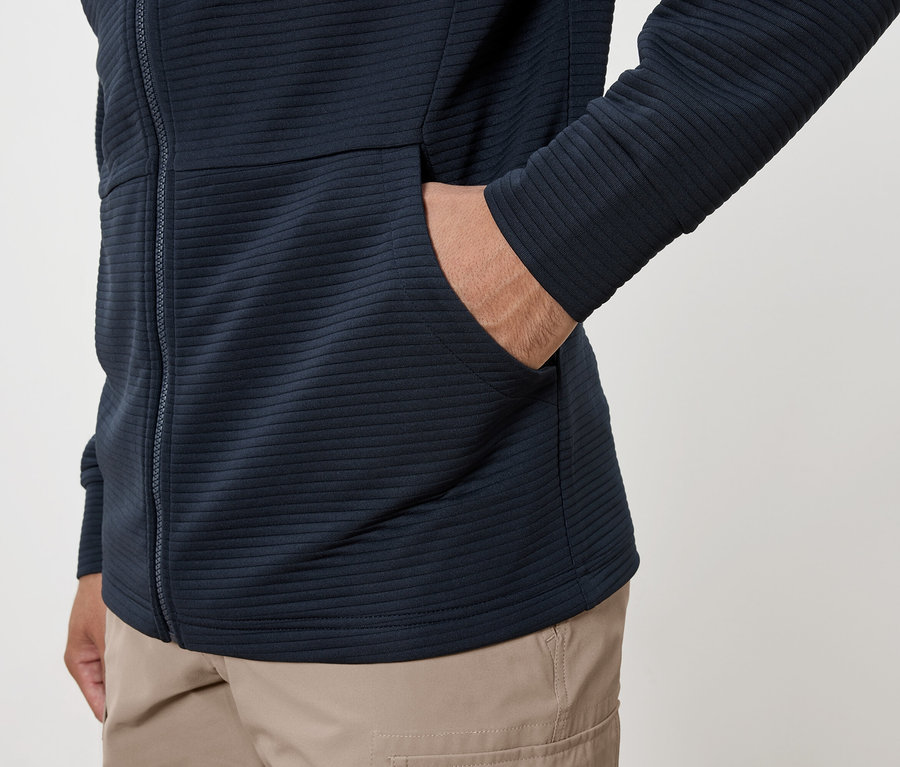 Homme avec la main dans la poche d'un sweat à capuche bleu marine et d'un pantalon cargo.