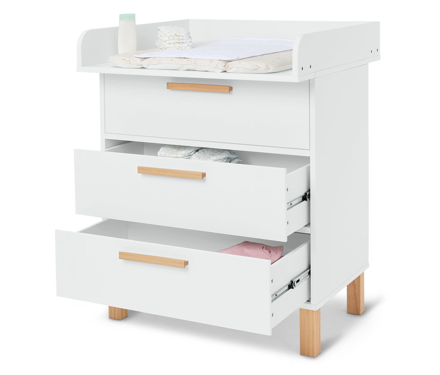 Table à langer blanche avec trois tiroirs, dont deux sont partiellement ouverts et montrent des couches et des vêtements de bébé.