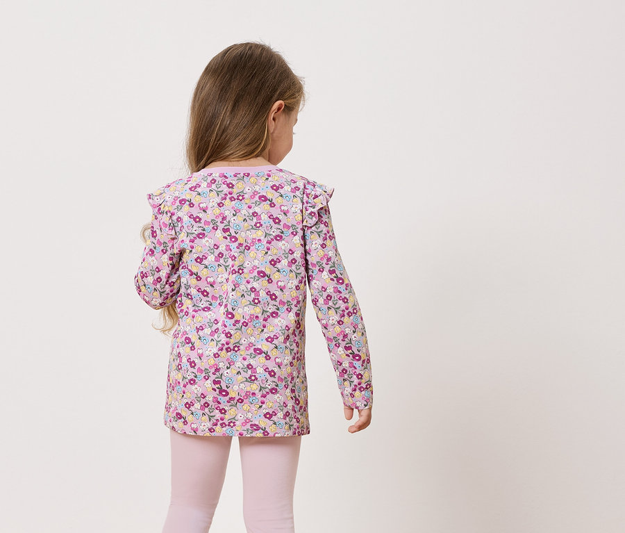 Vue de dos d'une petite fille aux cheveux longs portant un haut à manches longues à fleurs et un legging rose.