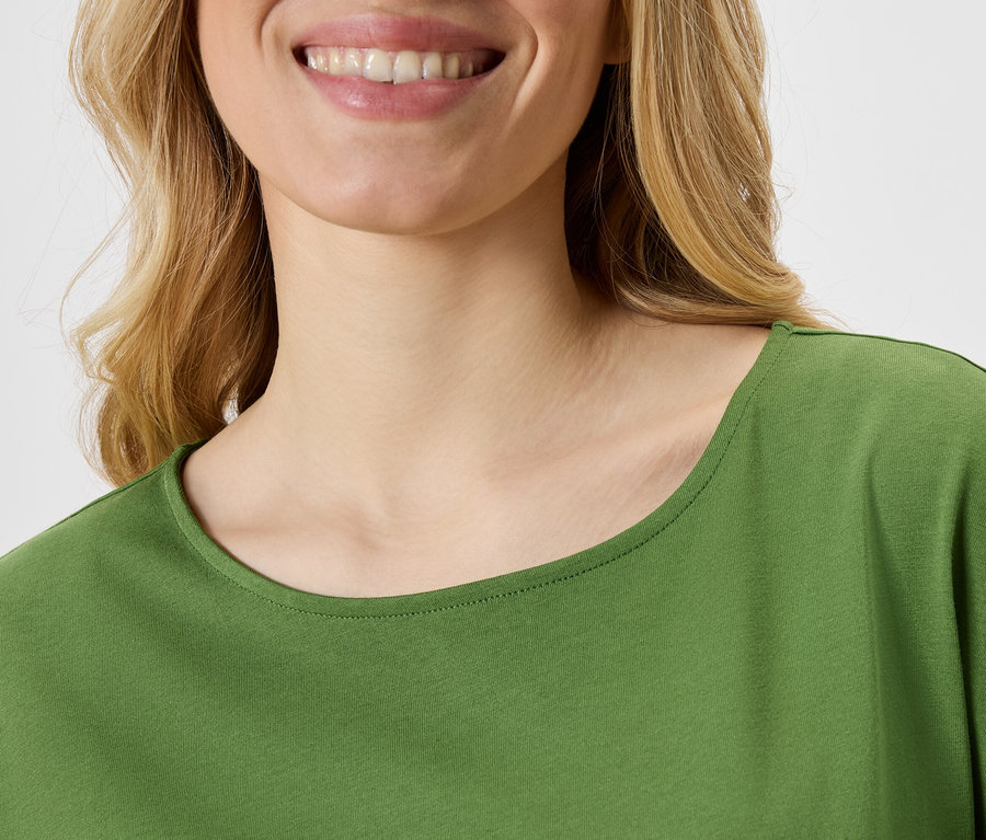 Gros plan d'une femme souriante portant un haut vert.