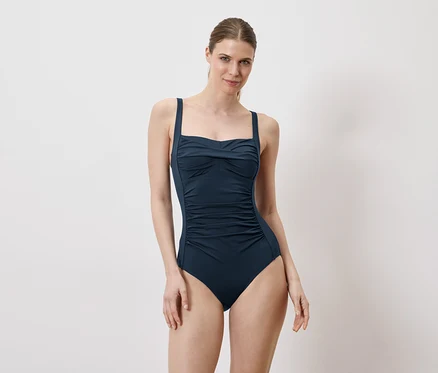 Femme portant un maillot de bain bleu marine sur fond blanc.