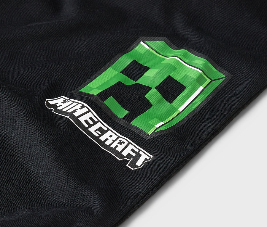 Gros plan sur un vêtement noir avec un motif Minecraft Creeper vert.