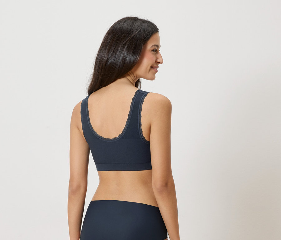 Femme portant un soutien-gorge bleu marine avec bordure en dentelle et des sous-vêtements assortis, vue de dos.