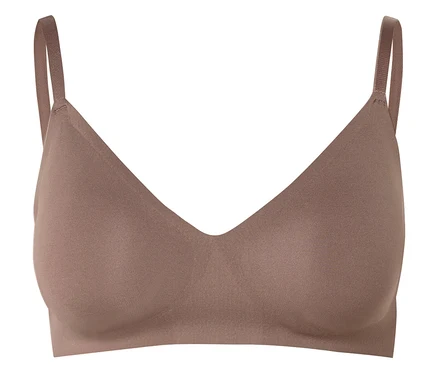 Un soutien-gorge couleur chair avec une encolure en V et de fines bretelles sur un fond blanc.