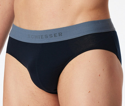 Un homme porte un slip SCHIESSER noir avec une ceinture grise sur laquelle est inscrit le nom de la marque.