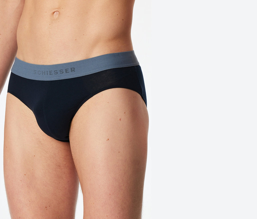 Gros plan d'une personne portant un slip noir Schiesser avec une ceinture grise.