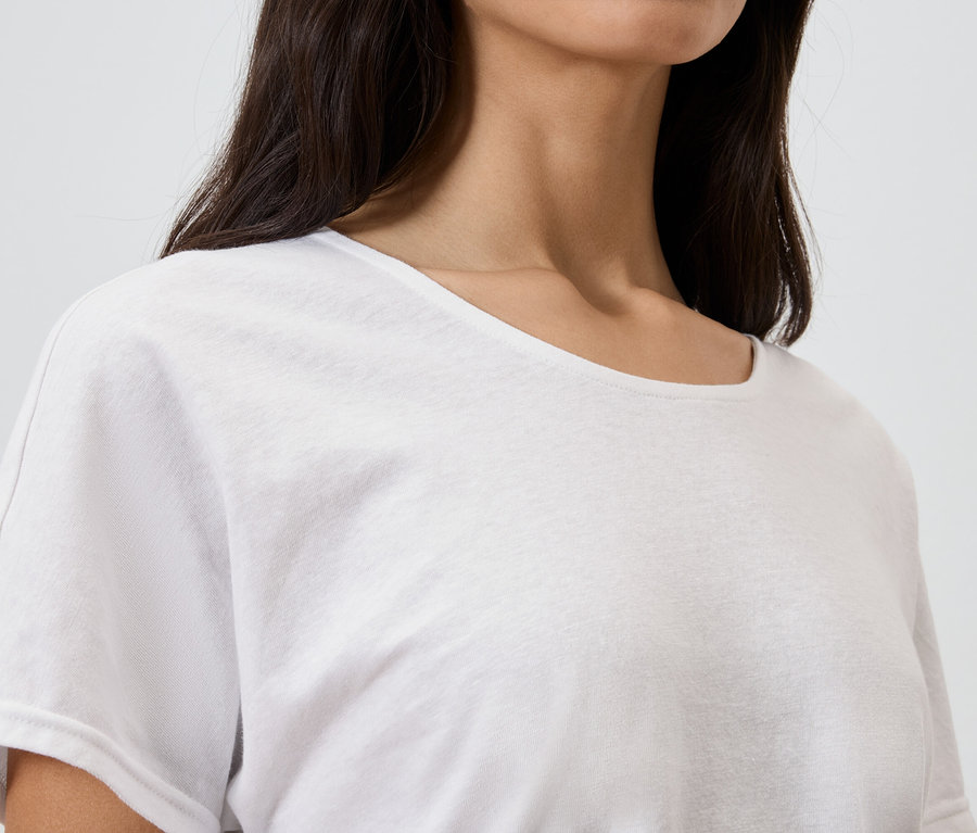 Gros plan d'une femme aux cheveux foncés portant un t-shirt blanc.