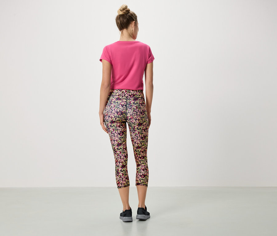 Vue arrière d'une femme portant un chignon, un t-shirt rose et un legging à fleurs.