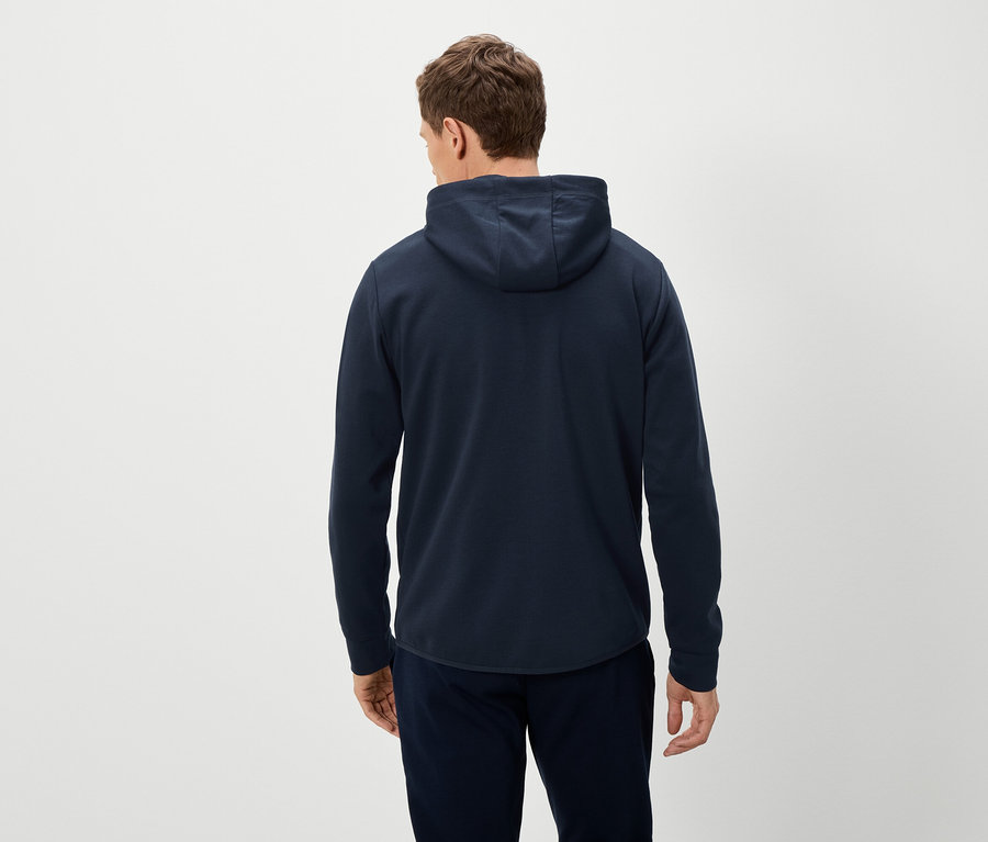 Vue de dos d'un homme portant un sweat à capuche bleu marine et un pantalon bleu marine sur un fond clair.