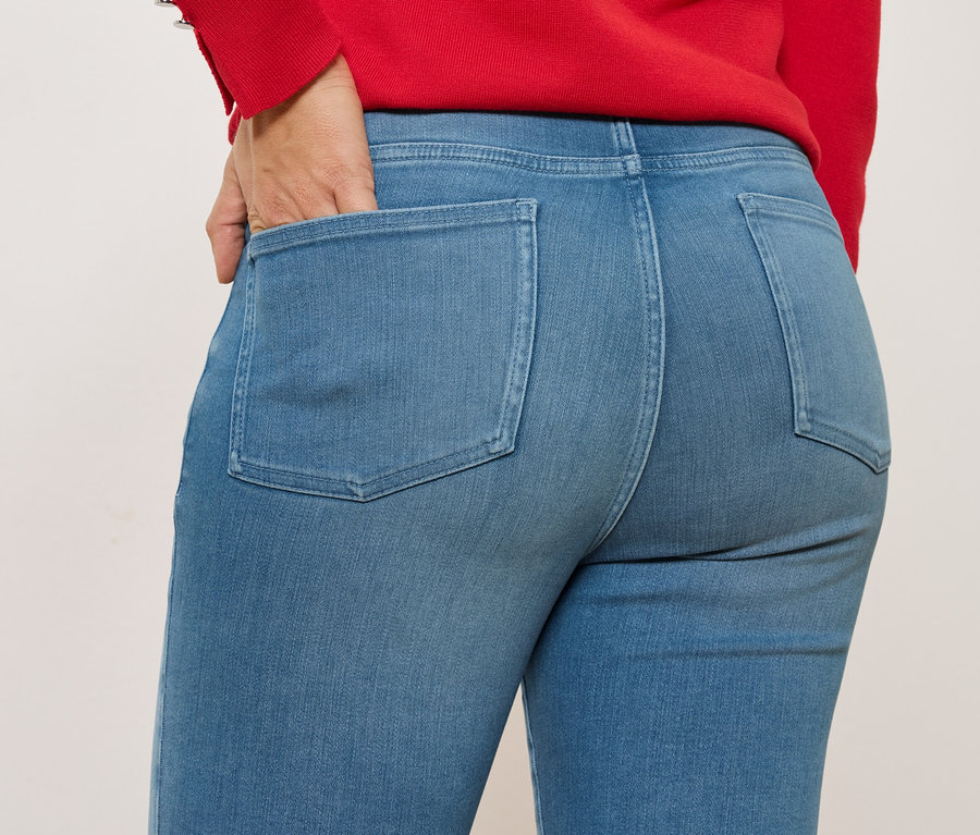 Gros plan d'une personne portant un jean bleu avec une main dans la poche arrière, porté avec un haut rouge.