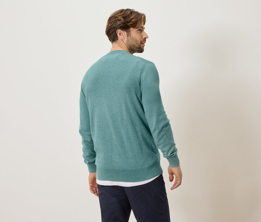 Homme vu de dos portant un pull turquoise et un pantalon bleu.