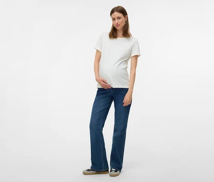 Femme enceinte portant un t-shirt blanc et un jean évasé MAMALICIOUS « MLEDINA » posant sur fond blanc.