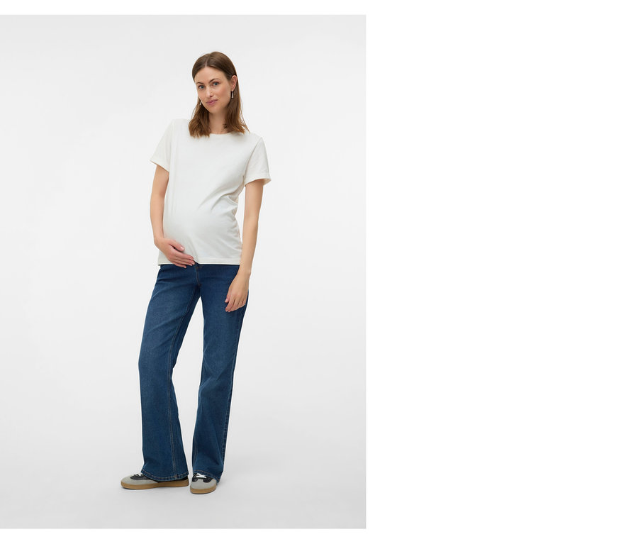 Femme enceinte portant un t-shirt blanc et un jean bleu, les mains posées sur son ventre.