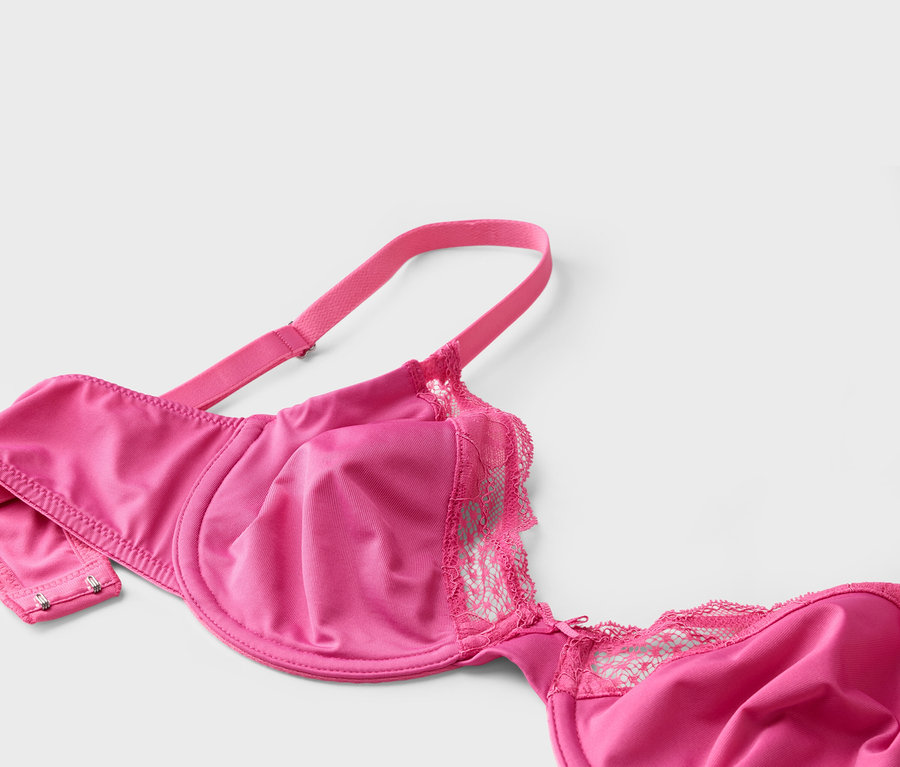 Gros plan d'un soutien-gorge rose avec de la dentelle sur un fond blanc.