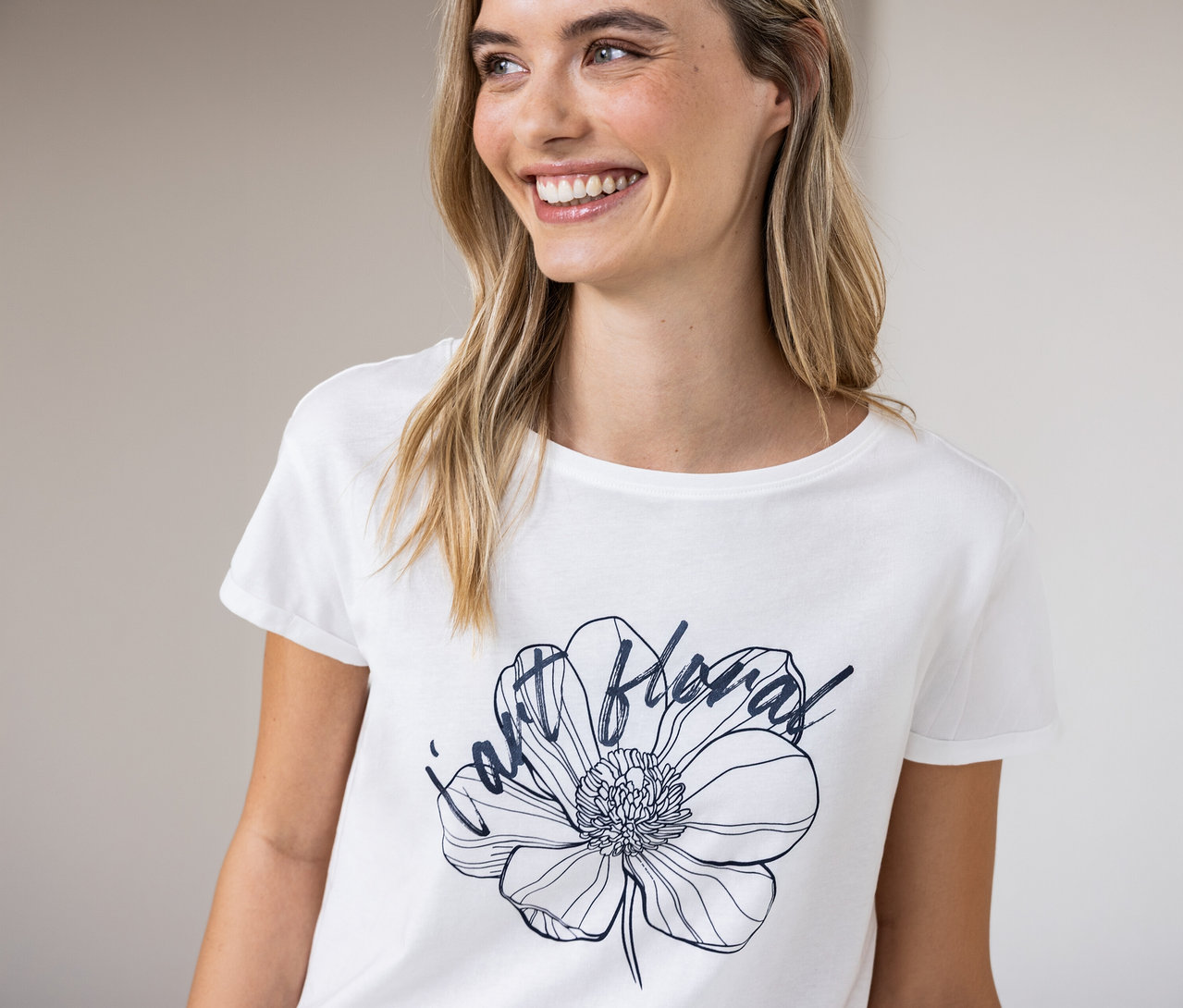 Une femme souriante porte un t-shirt Street One blanc avec un motif floral.