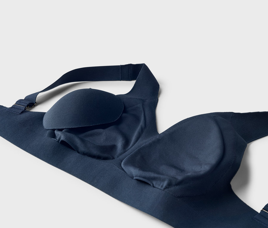 Gros plan d'un soutien-gorge bleu marine avec une bretelle réglable et des coussinets amovibles sur fond blanc.