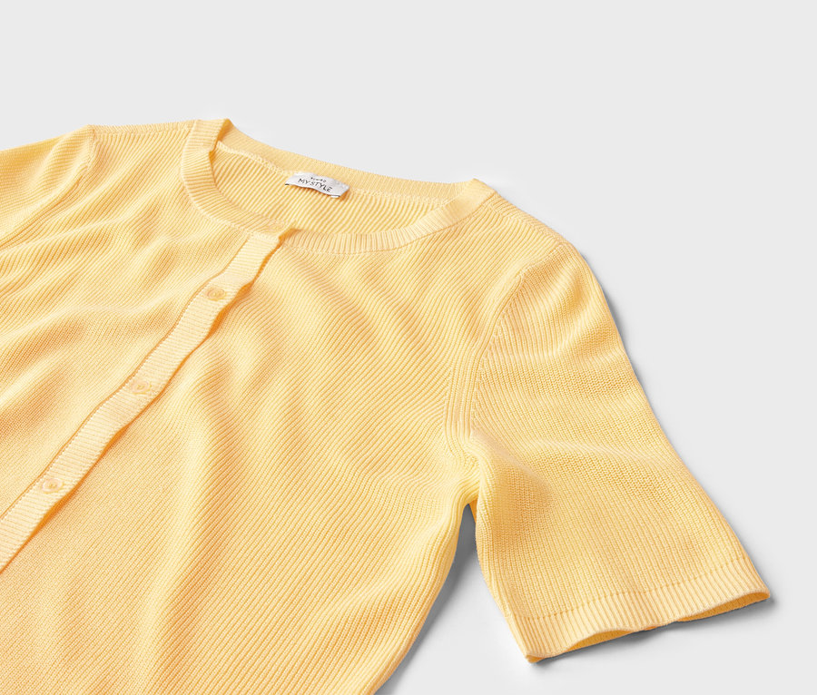 Gros plan d'un cardigan jaune clair côtelé à manches courtes et boutons sur fond blanc.