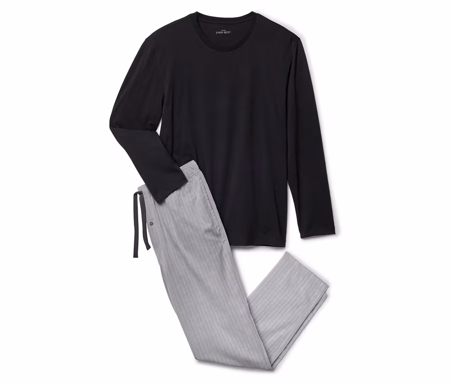 Un t-shirt noir à manches longues et un pantalon de pyjama gris rayé sont posés sur un fond blanc.