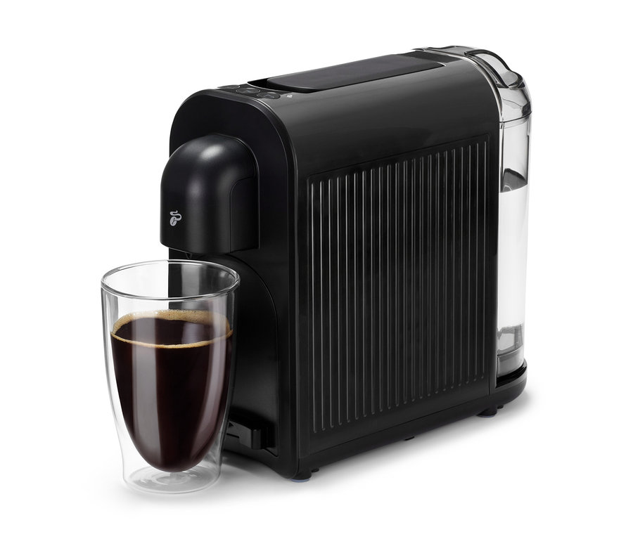 Une machine à café noire Cafissimo now black à côté d'un verre de café.