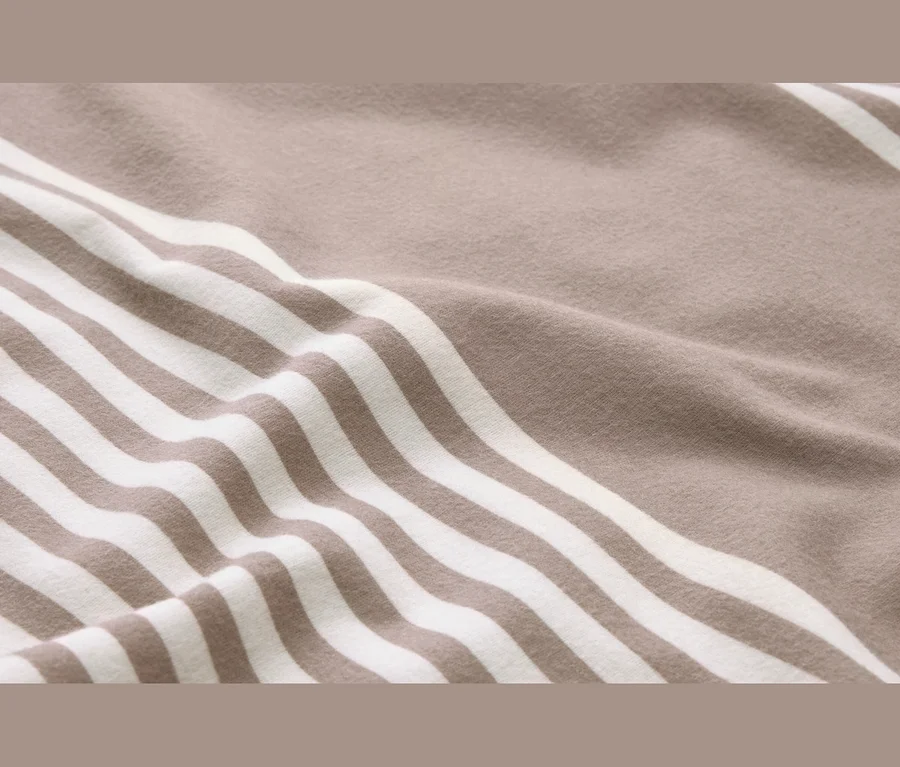 Gros plan d'un tissu doux et froissé à rayures beiges et blanches.