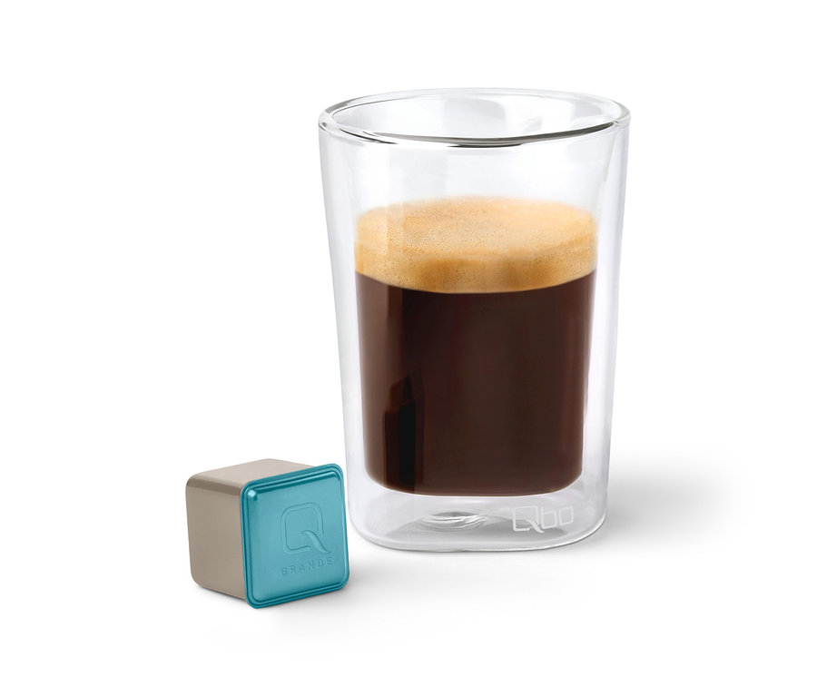 Capsule de café Qbo Caffè Grande KIRINYAGA BAYA à côté d'un verre de café.