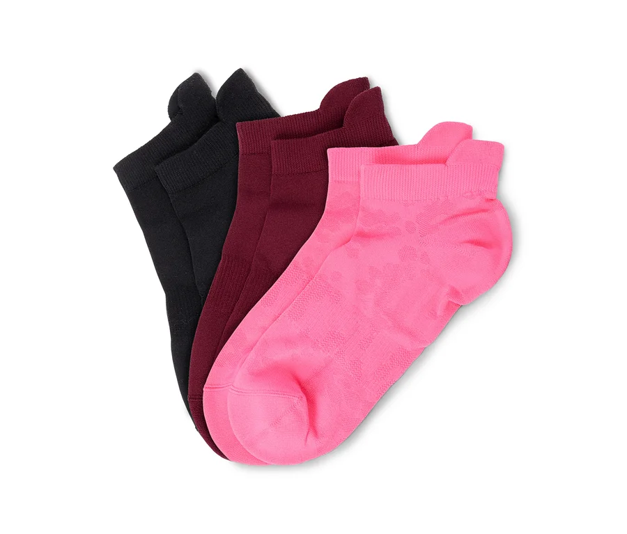 Trois chaussettes noires, bordeaux et roses, disposées en éventail sur un fond blanc. La chaussette rose présente un motif subtil.