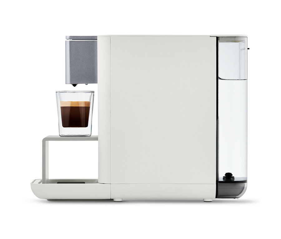Machine à café Qbo ESSENTIAL Bright Sand avec une tasse de café.