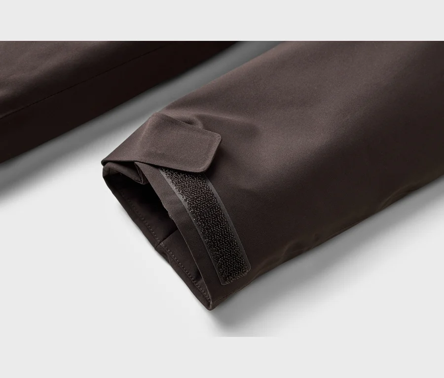 Gros plan d'un poignet de manche marron foncé avec une sangle Velcro réglable.