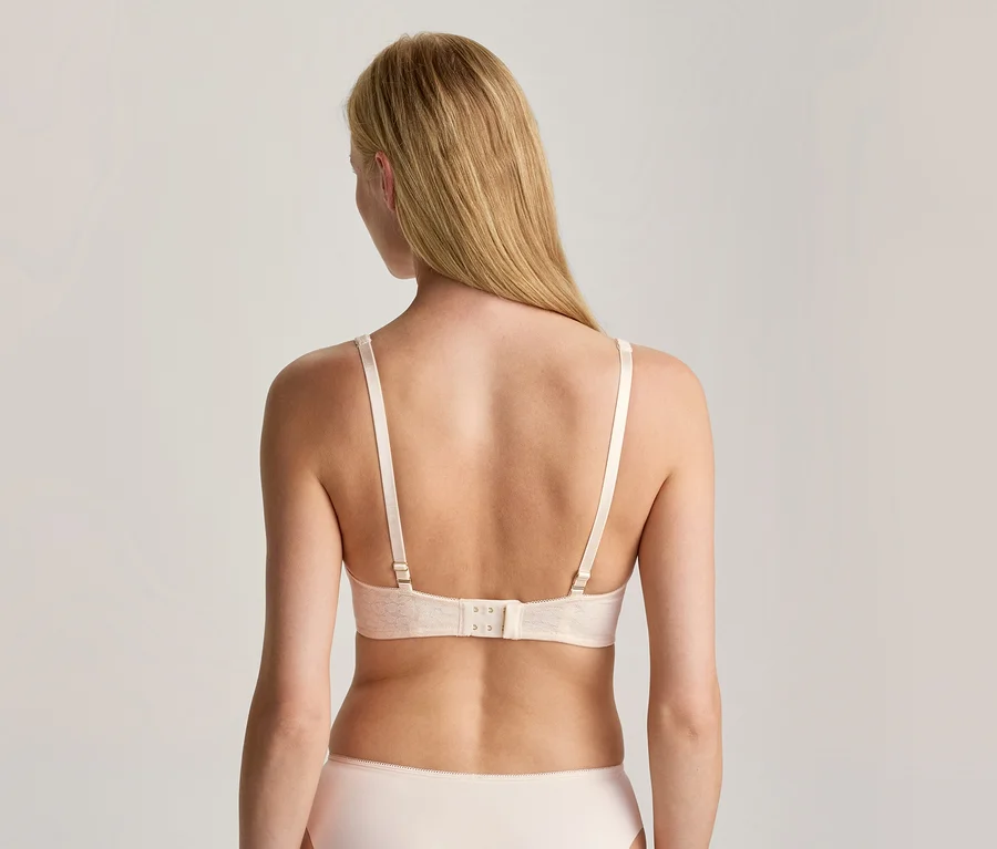 Femme de dos, portant un soutien-gorge et une culotte de couleur claire. Ses longs cheveux blonds tombent sur son dos.