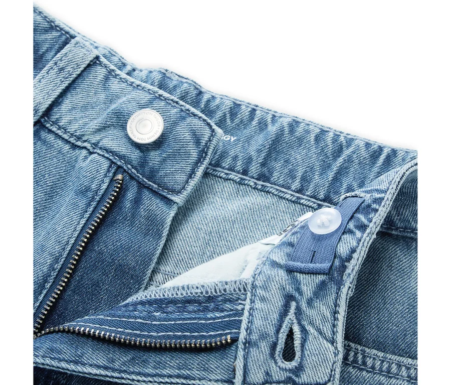 Gros plan d'un jean en denim bleu avec une braguette partiellement ouverte, un bouton métallique et une taille élastique ajustable avec un bouton en plastique.